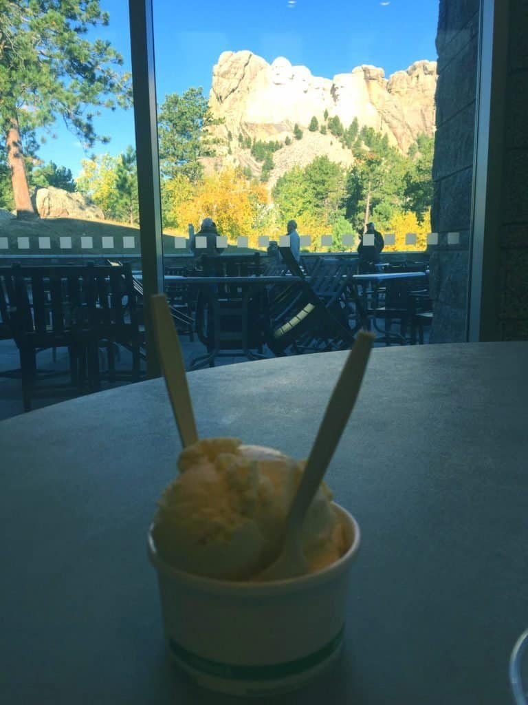 Ice Cream with two spoons on a table with a view of Mount Rushmore in the background, 