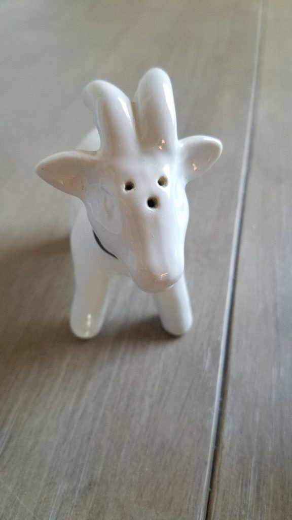 A white goat shaped pepper shaker on a table