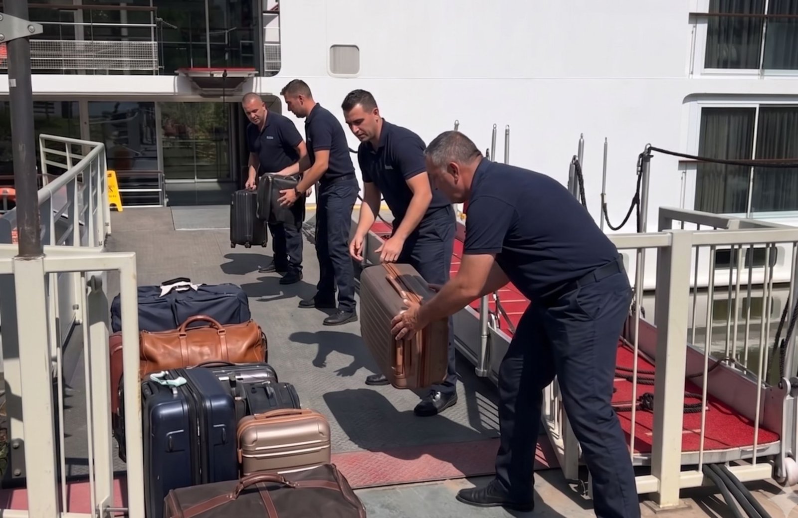 Crew members transferring luggage during a river cruise ship swap